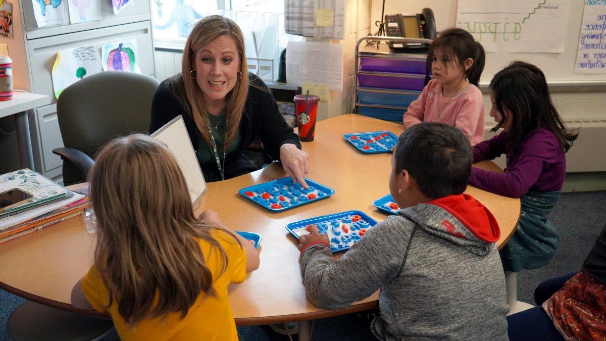 teacher with four students sitting around her at a table